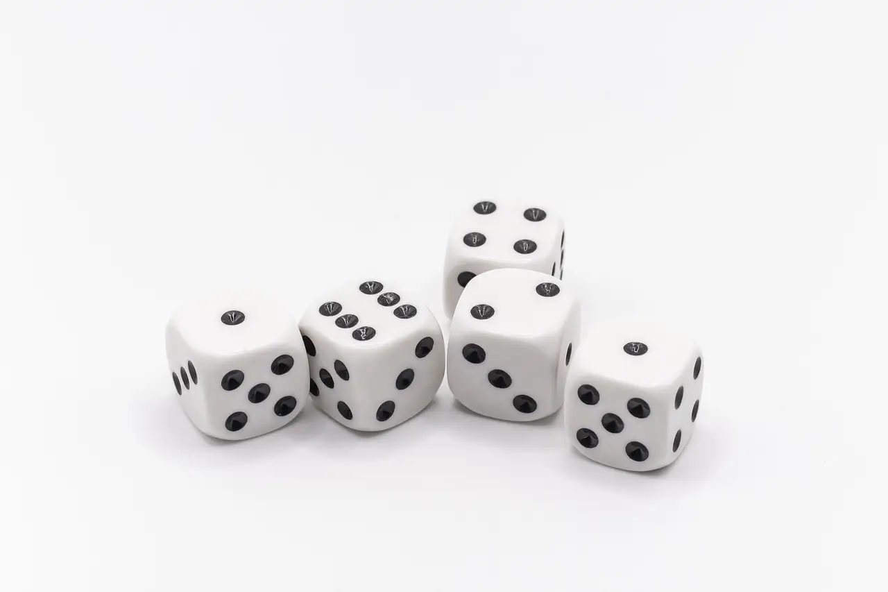 Five white dice with black dots arranged on a white surface