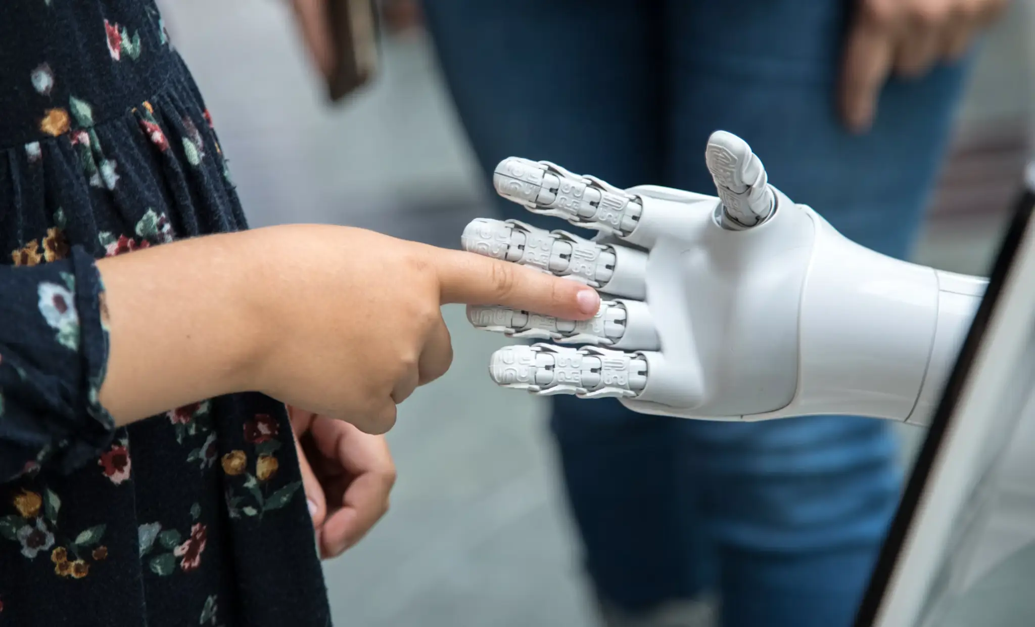 Human hand touching robotic hand in an interactive demonstration indoors
